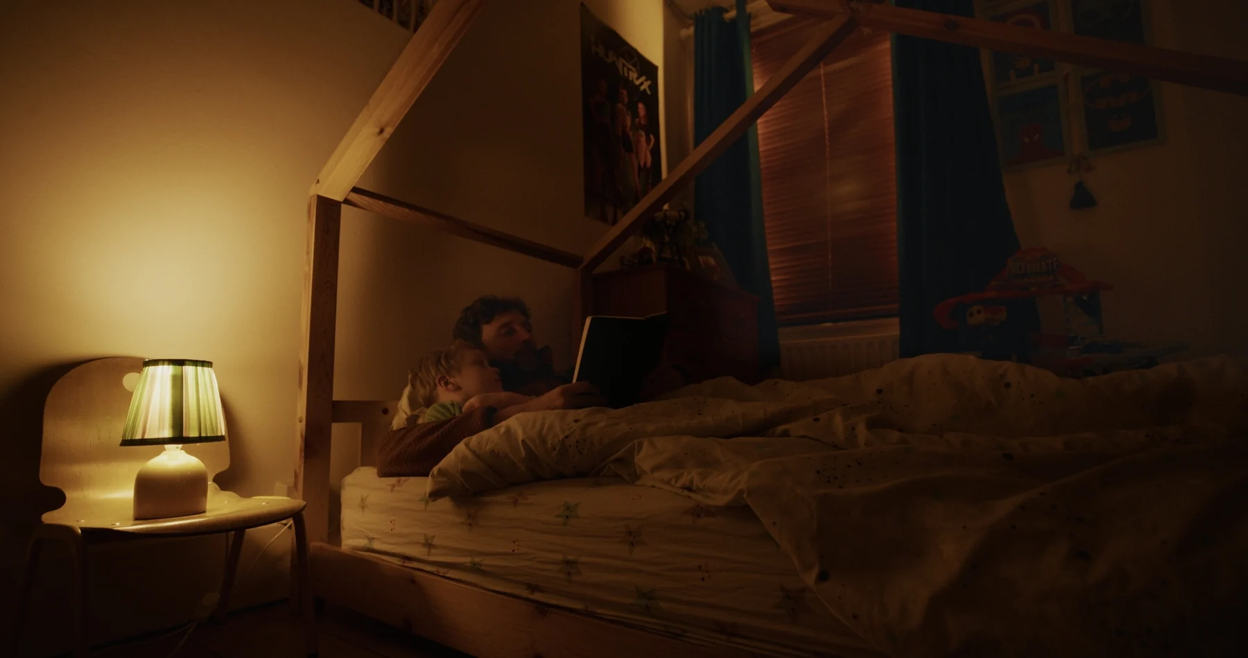 A parent and child reading together in a warmly lit bedroom