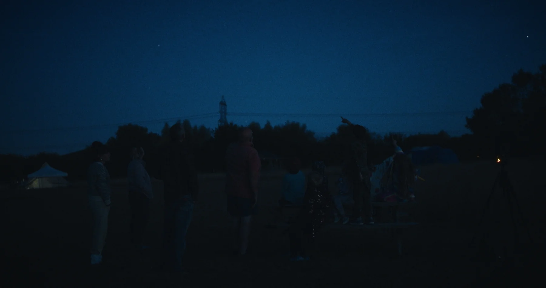 A group gathered outdoors beneath a dark blue evening sky