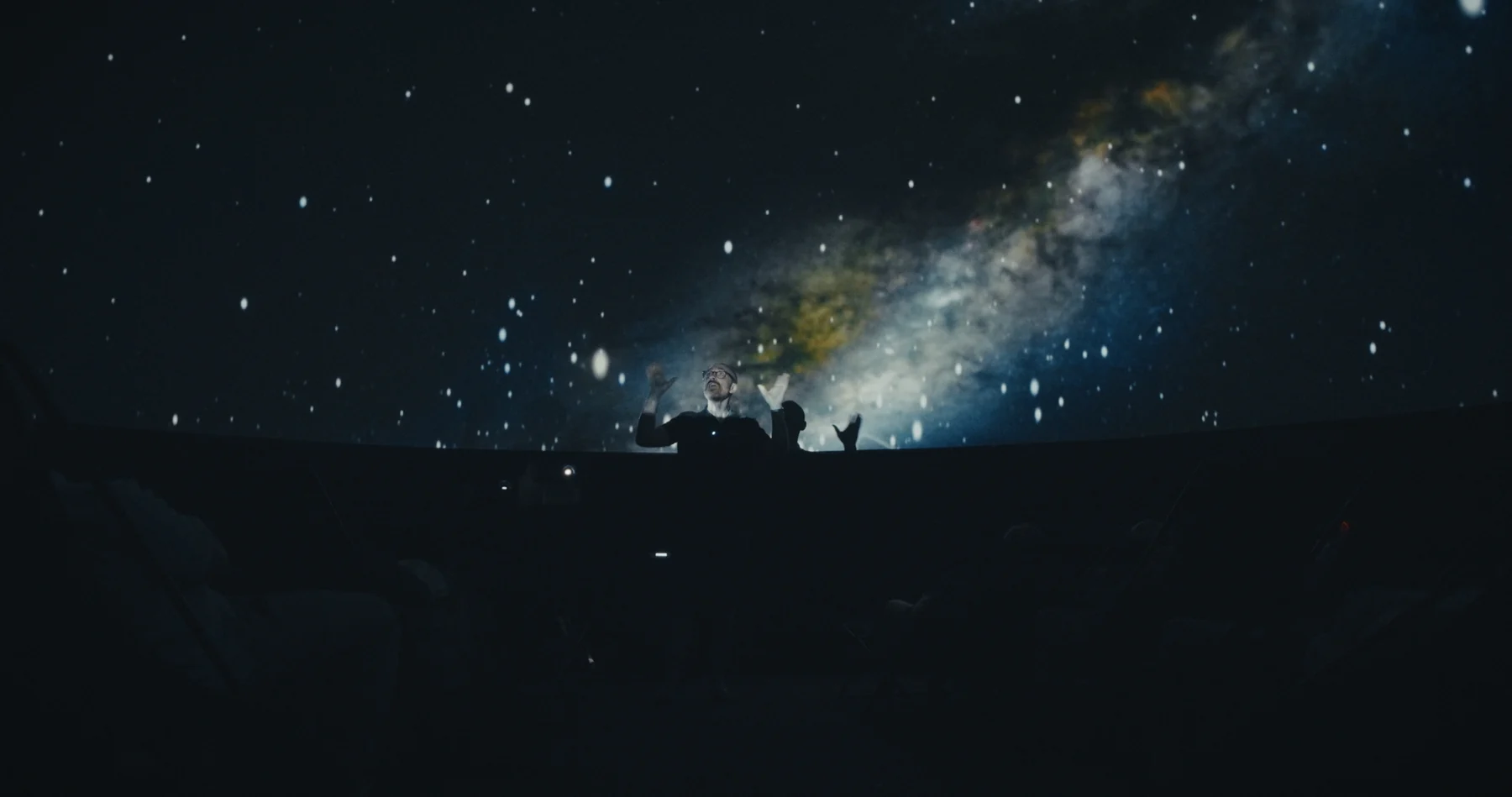 A projected Milky Way stretches across a dark planetarium dome